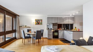 A modern apartment with a dining area, kitchen, and a large bed. - Krokus Apt.T by Interhome (Wengen)