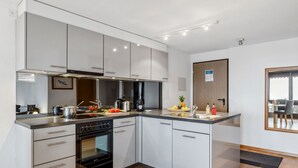 A modern kitchen with stainless steel appliances, white cabinetry, and a wooden floor. - Krokus Apt.T by Interhome (Wengen)
