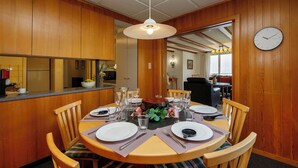 A dining area with a wooden table set for four, surrounded by chairs with striped cushions. - Chalet Shangri La by Interhome (Grindelwald)