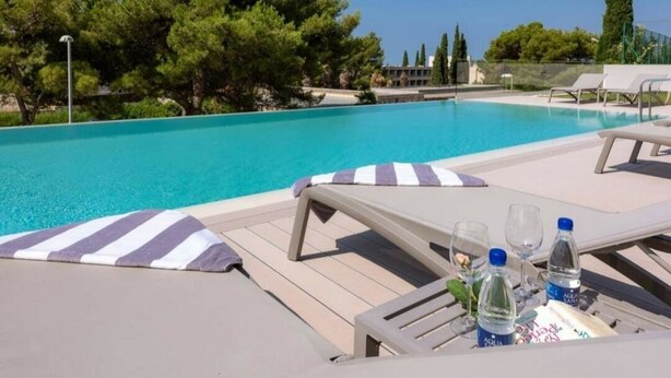 A poolside area with lounge chairs and a table with water bottles and glasses. - Bel Etage Luxury Rooms (Split)