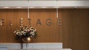A reception desk with a wooden wall and the word "ELÉTAGE" in large letters. There is a vase with flowers on the desk. - Bel Etage Luxury Rooms (Split)