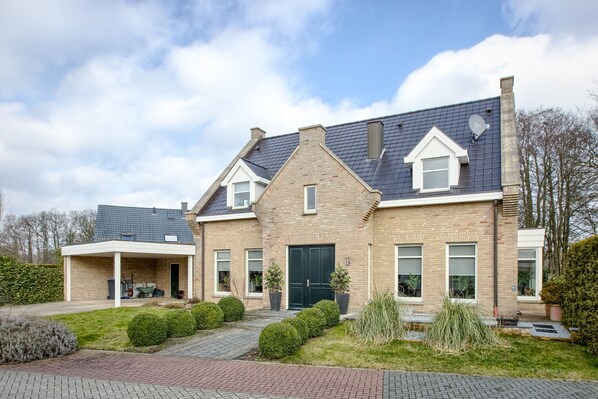 A two-story house with a brick exterior, a covered porch, and a well-maintained garden. - Villa Eltins (Bad Bentheim)