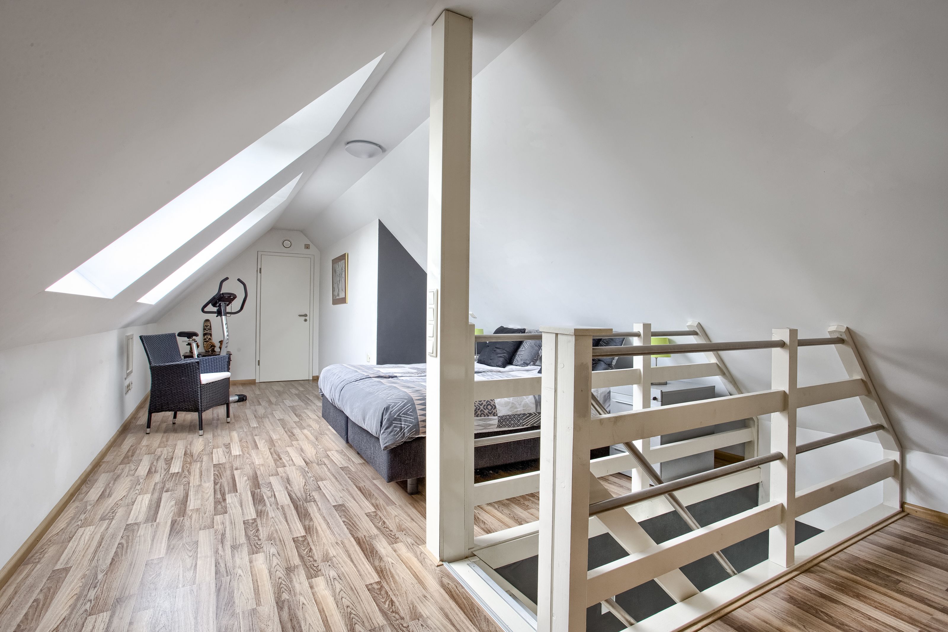 Un dormitorio con techo inclinado, una cama, un escritorio y una silla.