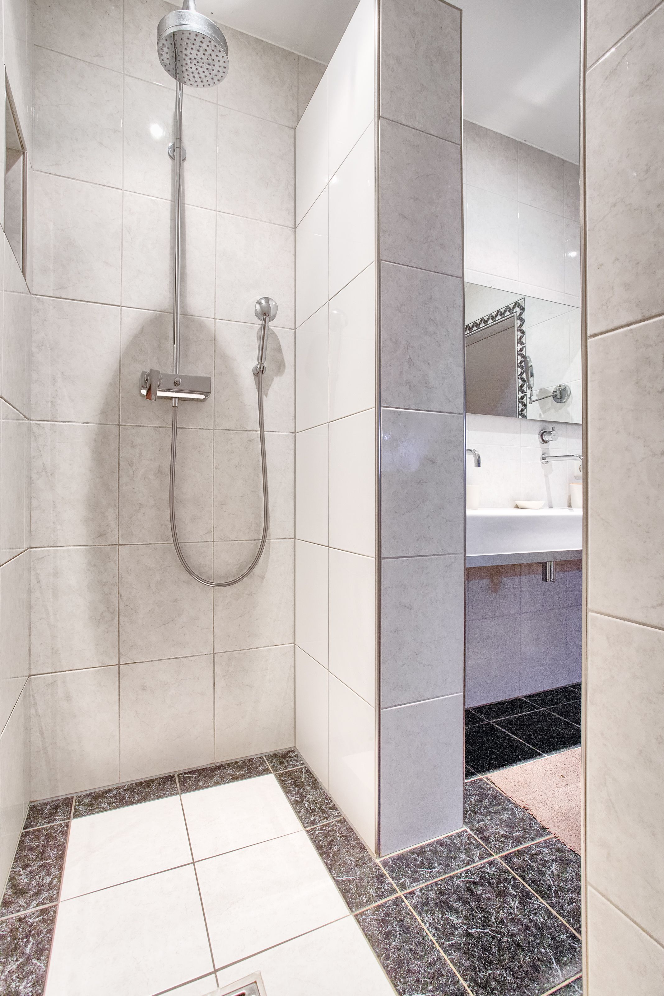 Une salle de bain avec une douche, un lavabo et un miroir.