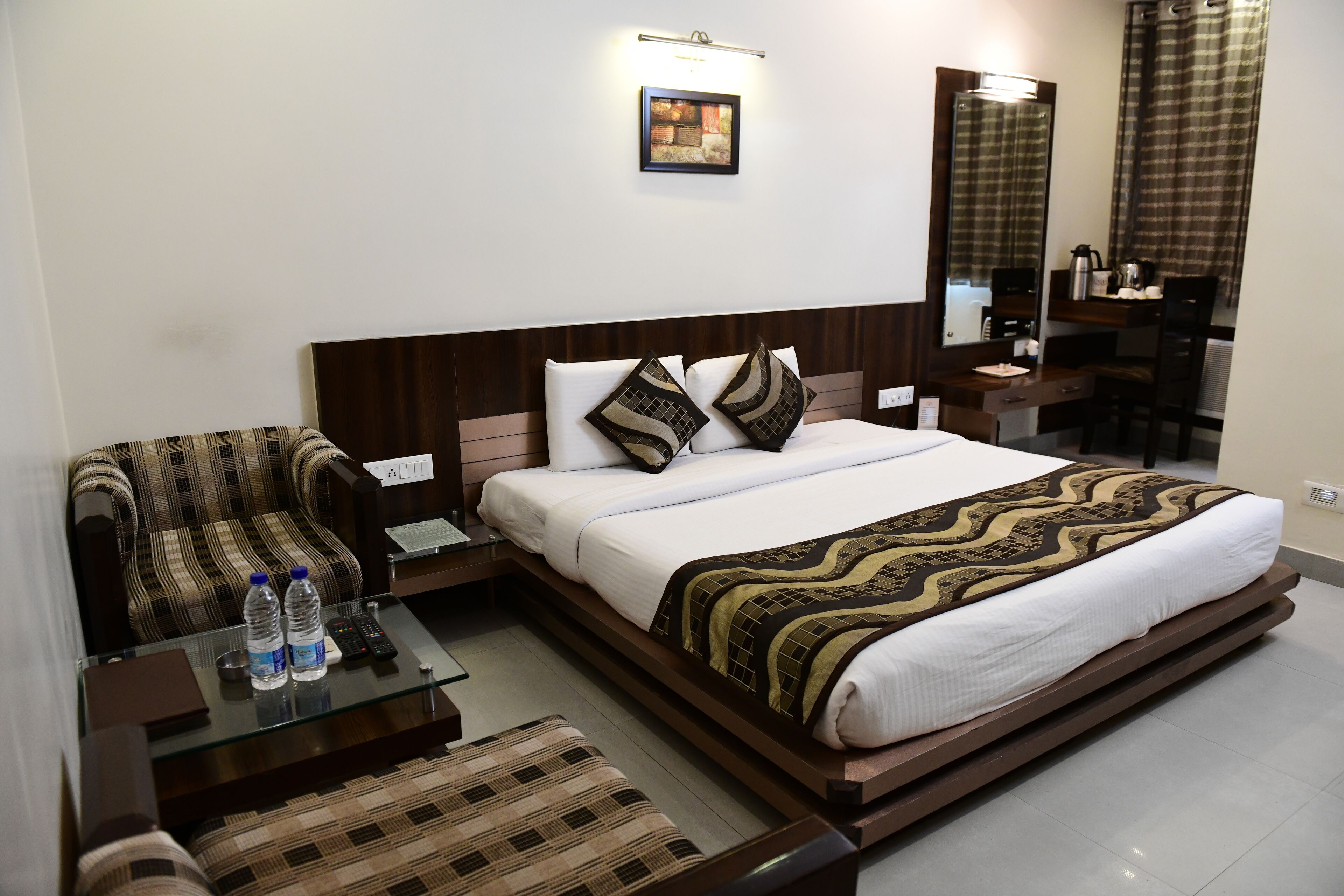 A hotel room with a bed, a chair, a desk, and a mirror.