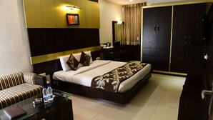 Une chambre d’hôtel comprenant un lit, un canapé, une table basse en verre, un bureau et une armoire.