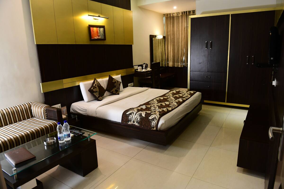 A hotel room with a bed, a sofa, a glass coffee table, a desk, and a wardrobe.