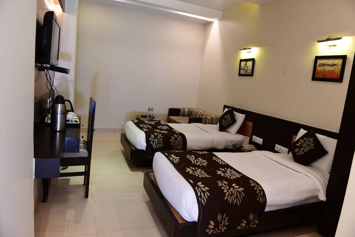 A hotel room with two beds, a desk, a chair, and a TV.