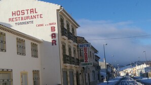 Un edificio con un letrero que dice "Hostal Restaurante Torrente" y "Carne a la Brasa Bar".