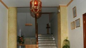 Una escalera con barandilla, un farol colgante y una planta en maceta.