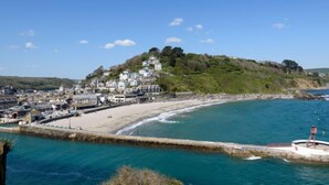 Une ville côtière dotée d’une plage, d’une jetée et de bâtiments situés sur une colline.
