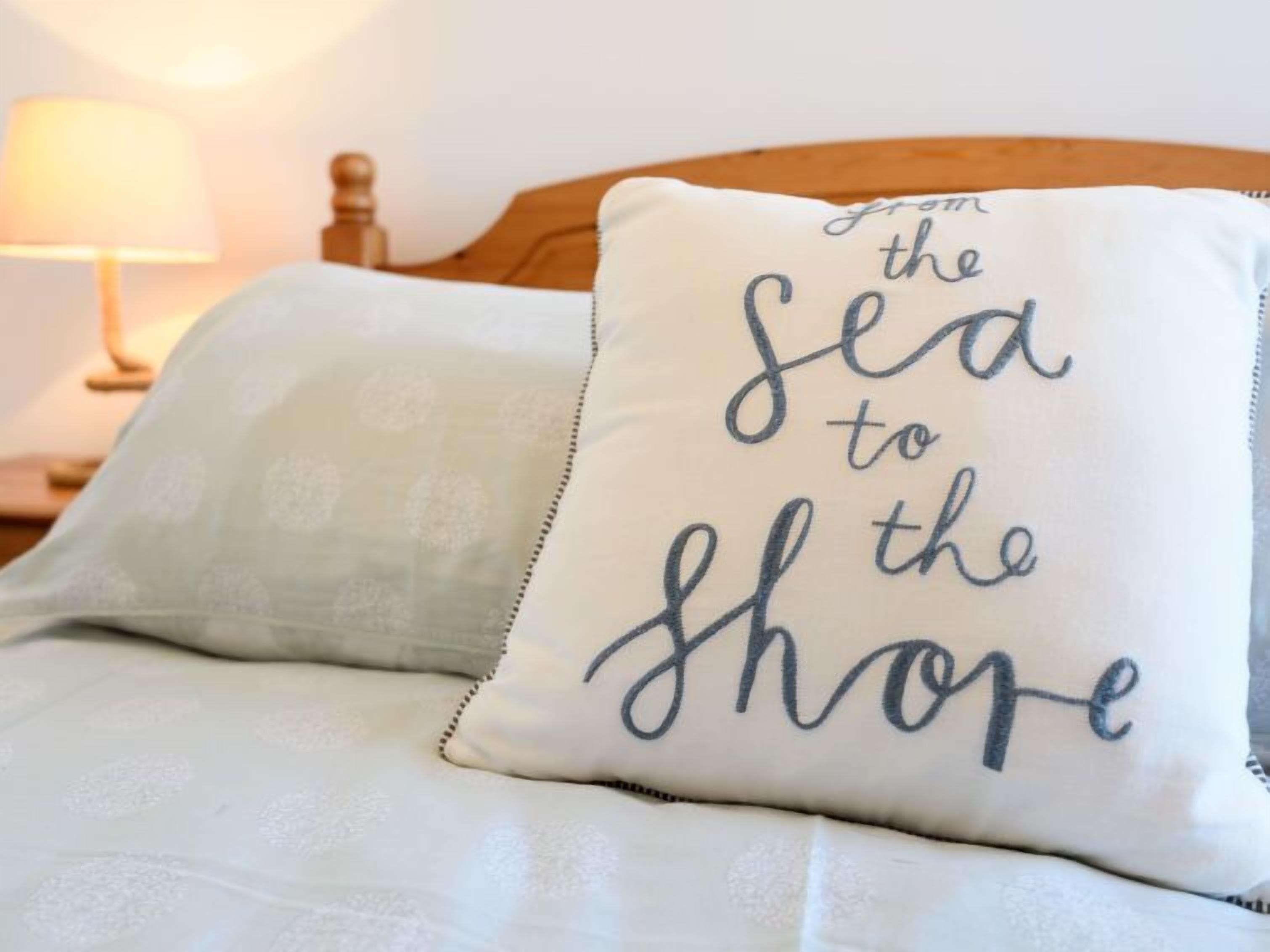 Een bed met een kussen waarop de tekst staat: ‘van de zee naar het strand’.