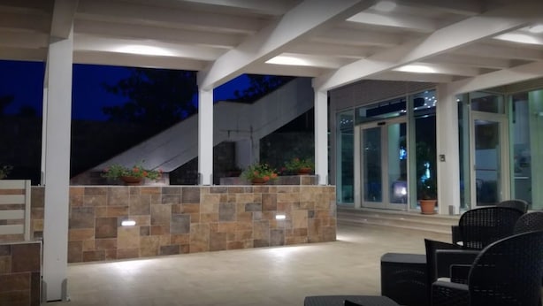 An outdoor patio area with stone walls, seating, and a staircase leading to an upper level. - Hotel Michelangelo (Teramo)