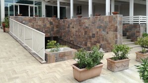A covered outdoor area with a stone wall, potted plants, and a white railing. - Hotel Michelangelo (Teramo)