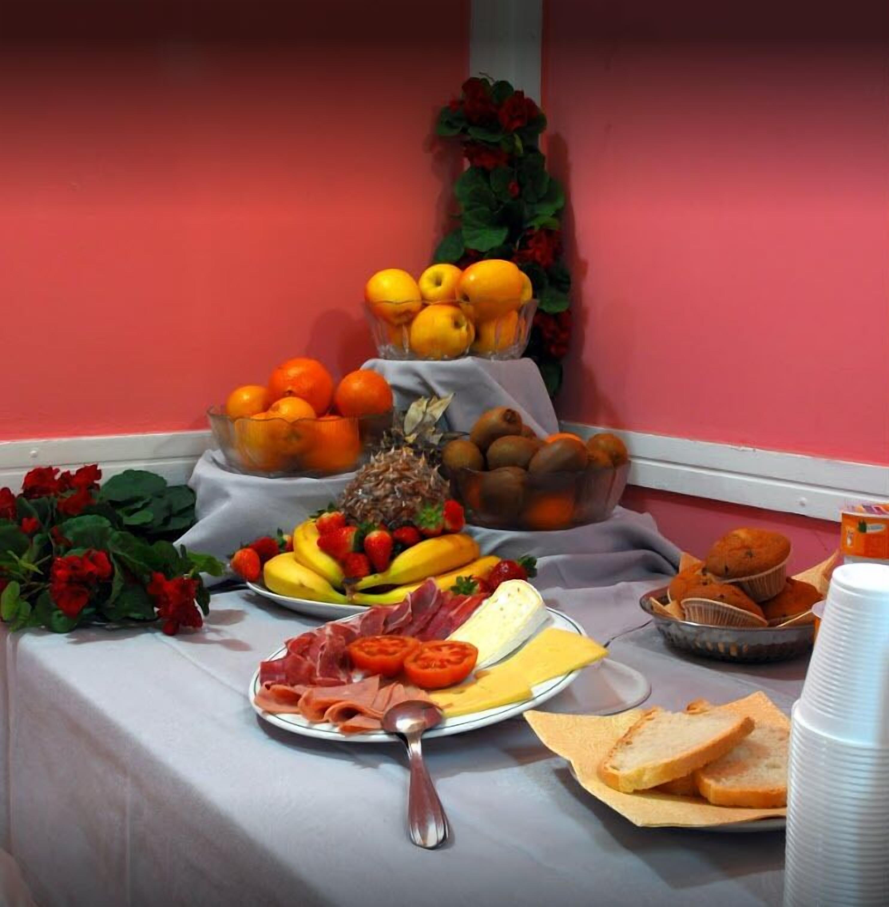 Una mesa de buffet con diversas opciones de comida, como frutas, queso y pan.