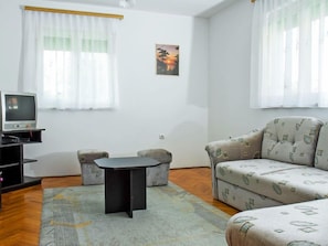 A room with a sofa, a small table, a TV on a stand, and a picture on the wall.