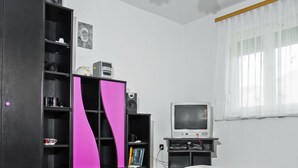 A living room with a black and pink cabinet, a television, and a small table. - Apartment Vilma by Interhome (Balatonmariafurdo)