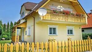 A two-story house with a balcony, a satellite dish, and a yellow fence. - Apartment Vilma by Interhome (Balatonmariafurdo)