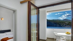 Un balcon avec une table et des chaises, un lit et une vue sur un paysage côtier.