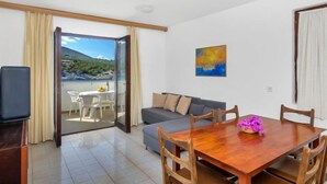 Une chambre moderne avec un balcon, un canapé, une table à manger et un tableau au mur.
