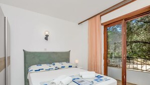 A bedroom with a bed, a nightstand, a wall-mounted lamp, and a sliding glass door leading to a balcony.