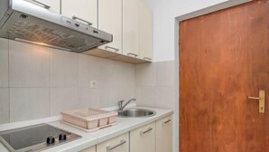 A kitchen with white cabinets, a stainless steel sink, a built-in oven, and a wooden door.