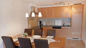 A modern kitchen with wooden cabinets, a dining table with chairs, and pendant lighting. - Grand Panorama C5 by Interhome (Nendaz)