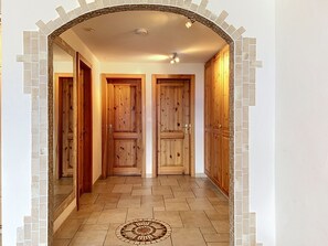 Un couloir avec des portes en bois, un sol carrelé et un motif décoratif en carreaux au bout.