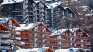 A cluster of multi-story wooden buildings with balconies, likely a hotel or resort, surrounded by snow-covered trees. - Grand Panorama C5 by Interhome (Nendaz)