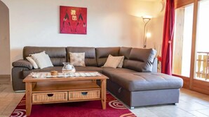 A living room with a brown leather sofa, a wooden coffee table, and a red patterned rug. - Grand Panorama C5 by Interhome (Nendaz)