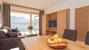 A modern living room with a wooden dining table, a sofa, and a TV on a wooden stand. - Kitzsteinhorn by Interhome (Zell am See)