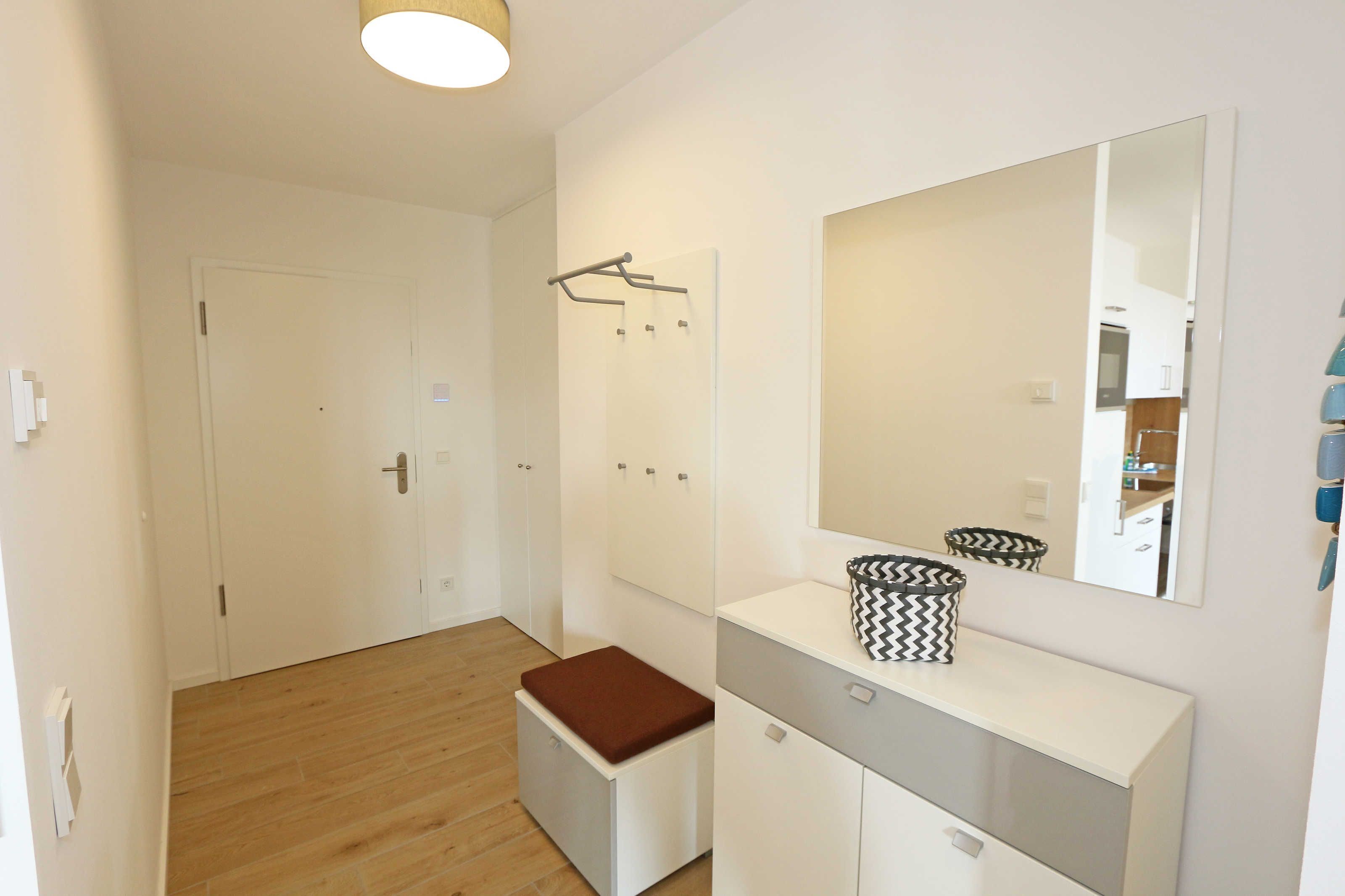 A modern bathroom with a white vanity, a mirror, and a bench.