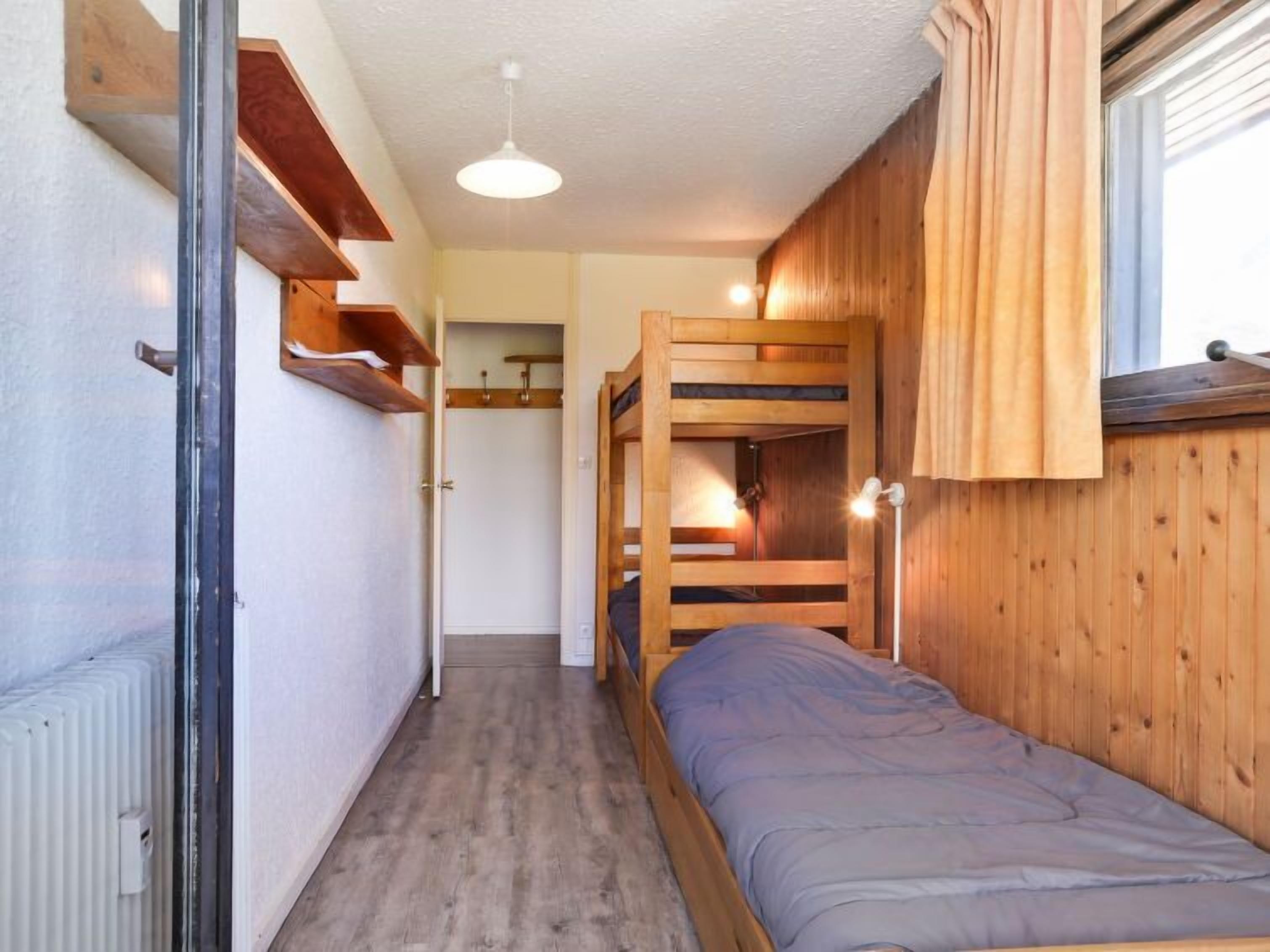 Une petite pièce avec un lit superposé, un petit placard et un radiateur.