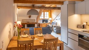 Ein gemütlicher Essbereich mit einem Holztisch und Stühlen, einem Kamin und einem Fernseher im Hintergrund.