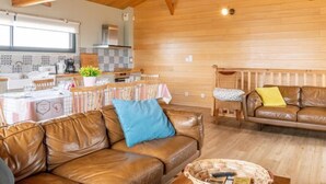A cozy interior with a wooden ceiling, a dining area with a table and chairs, and a leather sofa. - Les Mouettes by Interhome (Mimizan)