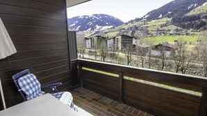 A balcony with a table and chairs, overlooking a mountainous landscape with houses. - Apartment Römer by Interhome (Bad Hofgastein)