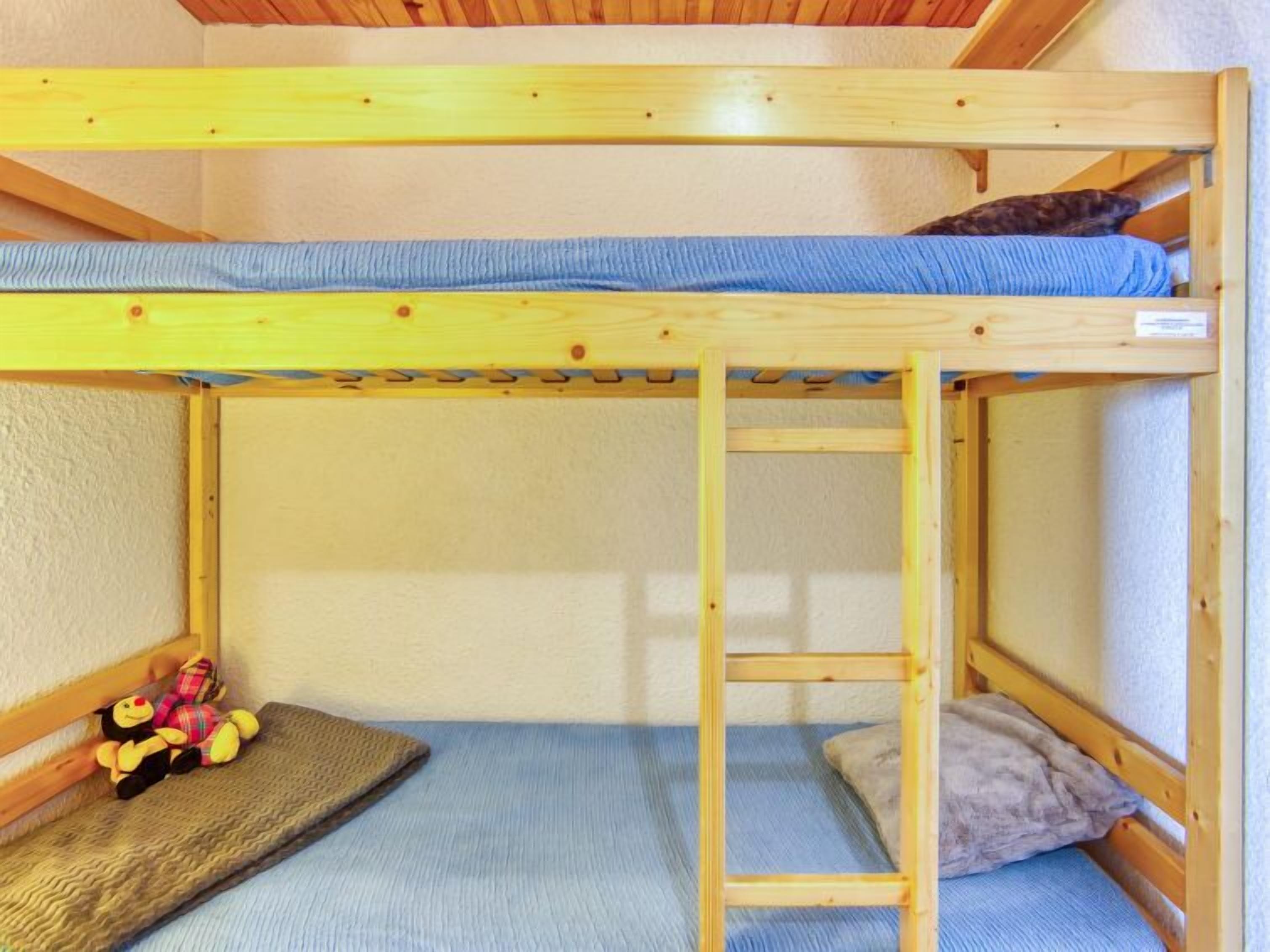 Ein Etagenbett mit einer Stehle, einer kleinen Ablage und einem Stofftier im unteren Bett.