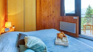 Un dormitorio con una cama, una bandeja de pasteles, una mesita de noche con lámpara y vistas al exterior.