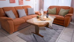 Ein Wohnzimmer mit zwei orangefarbenen Sofas, einem Holztisch und einem Teppich.