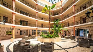 Un atrium à plusieurs niveaux, doté de meubles en osier, d’un jardinier central agrémenté de plantes et d’un revêtement de sol à motifs.