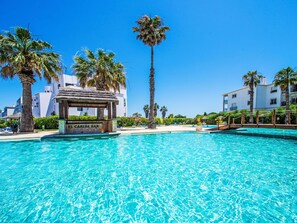 A clear blue pool with a sign reading "El Caribe Bar" and palm trees around. - Estrela do Vau.3 bedroom by Interhome (Portimão)