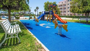 Une aire de jeux avec une zone de jeu bleue, un toboggan et un banc.