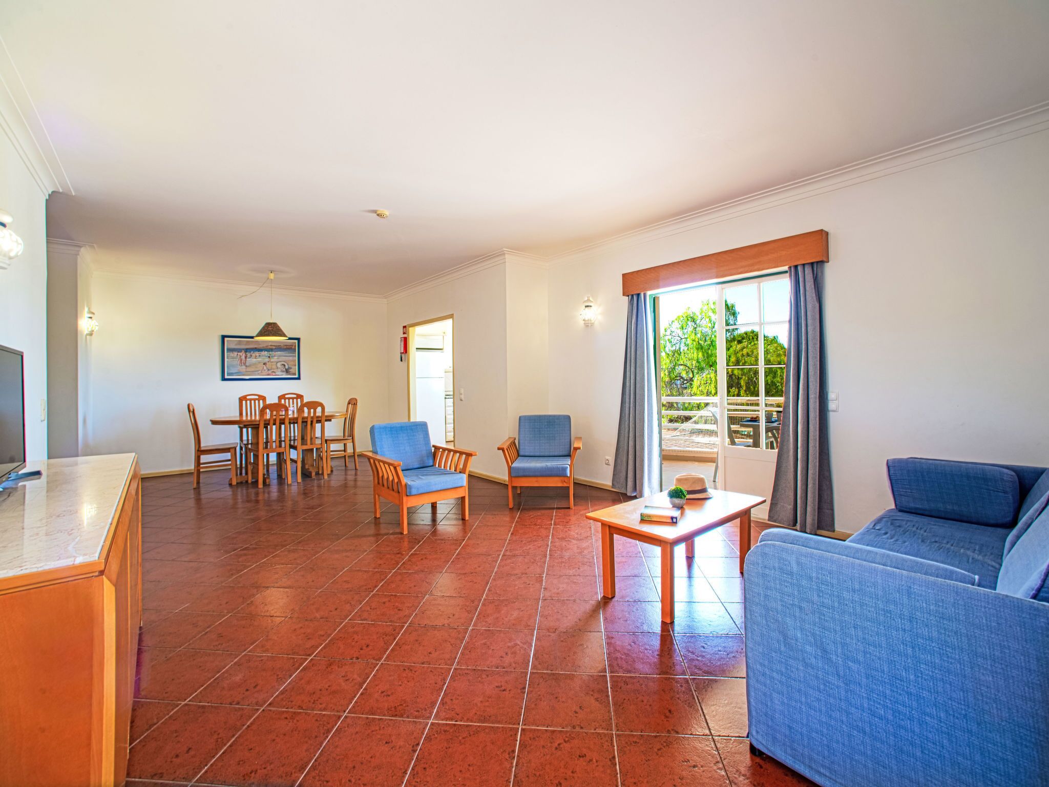Amplia sala de estar con comedor, sofá y vistas al exterior.