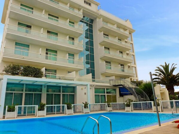 Un hôtel moderne doté d’une piscine, de nombreux balcons et d’une façade en verre.