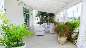 A covered outdoor area with white furniture, potted plants, and a view of the street. - Nautilus by Interhome (Vasto)
