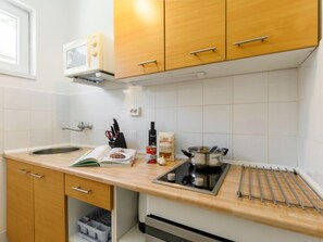 A kitchen with wooden cabinets, a microwave, a sink, and a stove. - Bercsényi by Interhome (Balatonboglar)