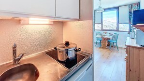 Una cocina con lavamanos, estufa y olla. Se ve un ventanal con vistas a un paisaje montañoso.