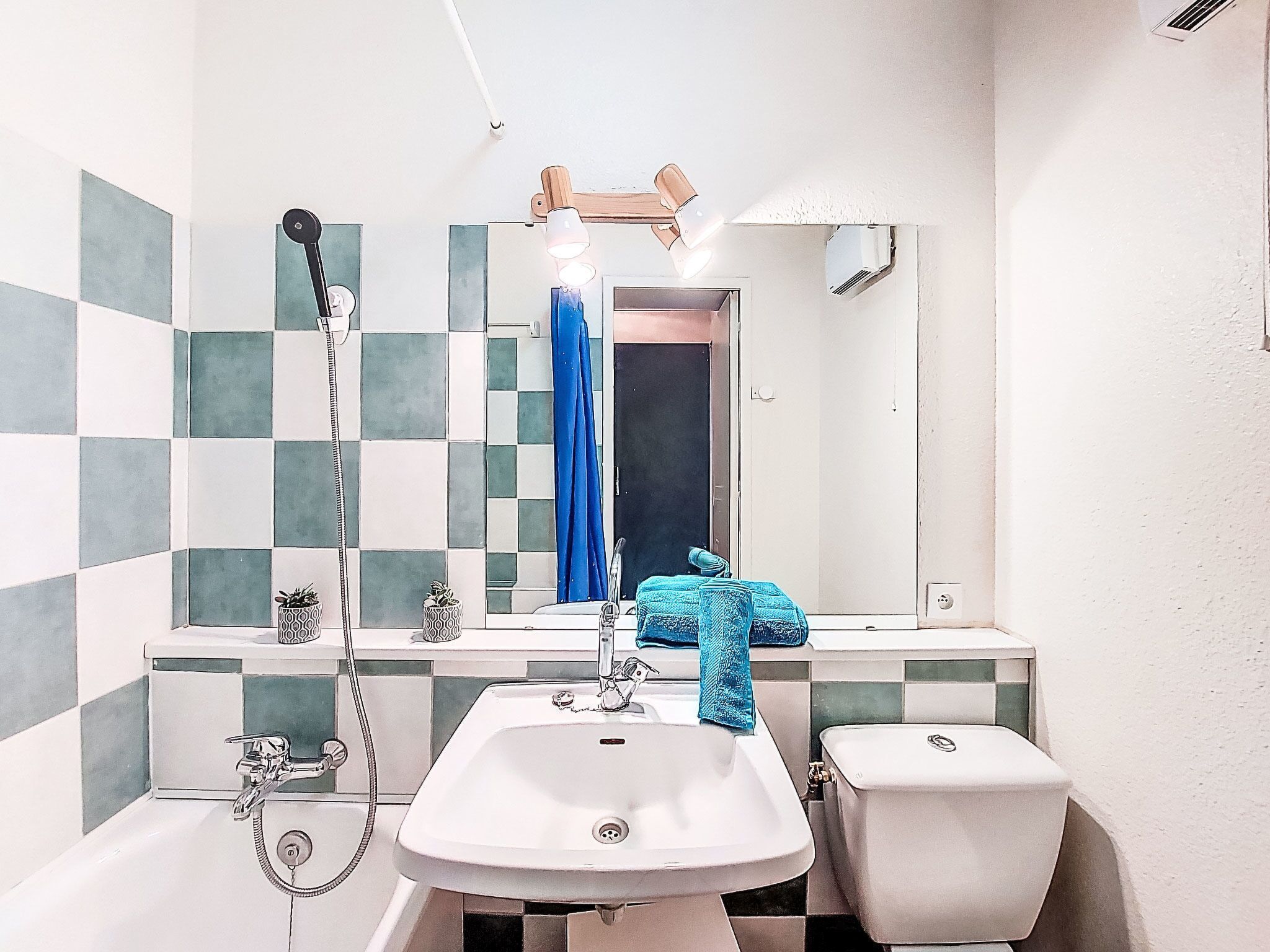 Een badkamer met een wit wastafel, twee toiletten, een spiegel en een douche.