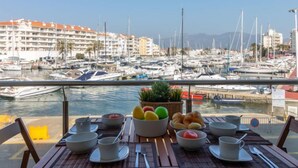 A dining table with bowls and fruits, overlooking a marina with boats and buildings. - Del Port by Interhome (Empuriabrava)