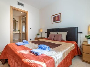 Une chambre d’hôtel avec un grand lit, une armoire en bois, une table de chevet avec une lampe et un tableau encadré au mur.